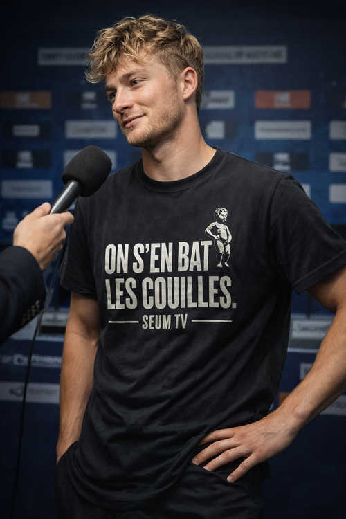 Homme portant le maillot noir On s’en bat les couilles SEUM TV pendant une interview avec micro.